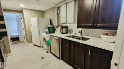 Compact kitchen area featuring dark wood-finish cabinetry, white countertops, and a white subway tile backsplash - 