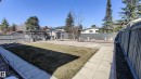 Expansive backyard featuring a central lawn area, concrete paver pathways, and a perimeter fence - 3311 108 Street, Edmonton, AB  - Outdoor 