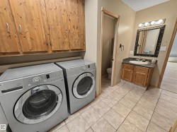 Laundry area featuring wood cabinetry, tiled flooring, and a vanity with an ornate mirror - 