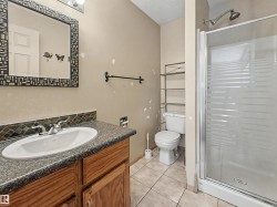 Bathroom featuring a vanity with wood-finish cabinetry, a speckled countertop, and a tiled backsplash - 