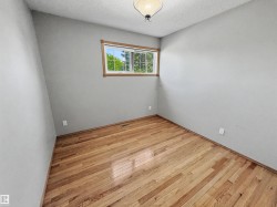 Interior room featuring wood-finish flooring, light grey painted walls, and a window with wood trim - 