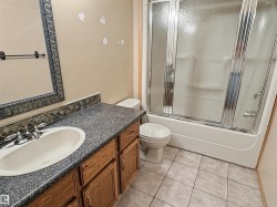 Bathroom featuring a wood-finish vanity with an integrated sink and speckled countertop - 