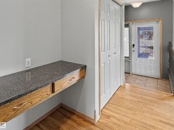 Entryway featuring light wood-finish flooring and a built-in desk with a dark flecked countertop - 
