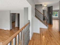 Hardwood flooring extends throughout the main level, complemented by a traditional wood staircase with painted balusters - 