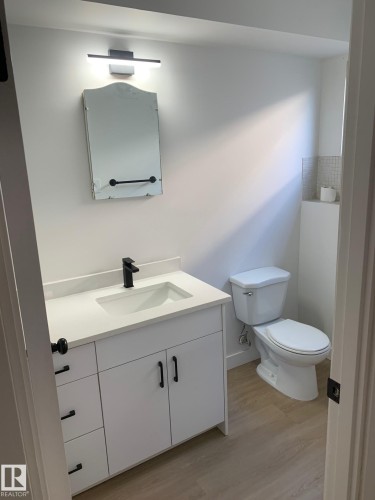 Bathroom featuring a white vanity with matte black hardware, integrated sink, and white countertop - 16321 - 109A Ave Nw, Edmonton, AB - Indoor Photo Showing Bathroom