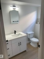 Bathroom featuring a white vanity with matte black hardware, integrated sink, and white countertop - 
