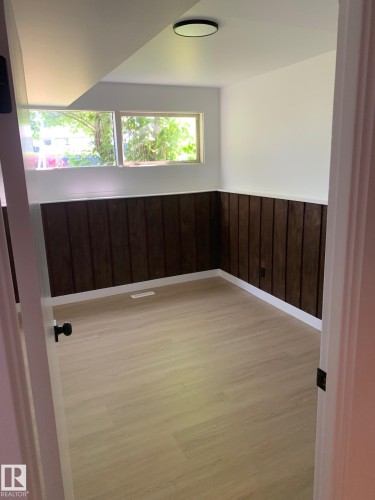 Light wood-finish flooring complements dark wood-paneled wainscoting - 16321 - 109A Ave Nw, Edmonton, AB - Indoor Photo Showing Other Room