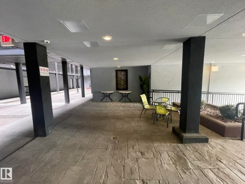 Covered outdoor walkway featuring stamped concrete flooring, black structural columns, recessed lighting, and a decorative planter box with landscaping - 504 10518 113 Street, Edmonton, AB - Indoor Photo Showing Other Room