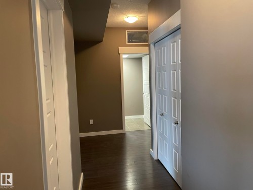 Hallway featuring wood-finish flooring, white trim, recessed lighting, and a bi-fold door - 504 10518 113 Street, Edmonton, AB - Indoor Photo Showing Other Room