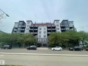 Contemporary multi-story building featuring varied facade materials including light and dark panels, multiple balconies with glass railings, and a prominent ground-level entrance - 504 10518 113 Street, Edmonton, AB  - Outdoor With Balcony With Facade 