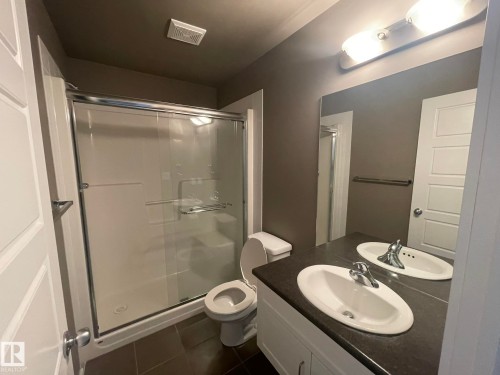 Bathroom featuring a double vanity with integrated sinks, a chrome faucet, and a large mirror - 504 10518 113 Street, Edmonton, AB - Indoor Photo Showing Bathroom