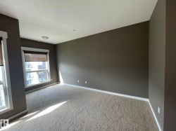Carpeted room featuring two windows with roller shades, neutral gray walls, white baseboards, and a flush-mount ceiling light fixture - 