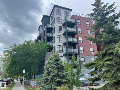 Multi-story building featuring a brick and panel facade, multiple balconies with glass railings, and ground-level commercial frontage - 504 10518 113 Street, Edmonton, AB - Outdoor With Balcony With Facade