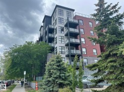 Multi-story building featuring a brick and panel facade, multiple balconies with glass railings, and ground-level commercial frontage - 