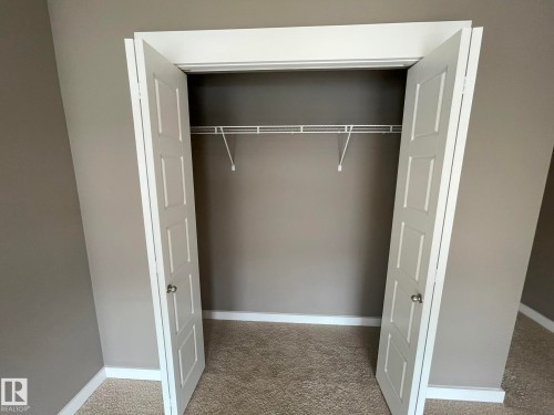 Reach-in closet featuring bi-fold panel doors, a single wire shelving unit, and carpet flooring - 504 10518 113 Street, Edmonton, AB - Indoor