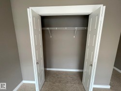 Reach-in closet featuring bi-fold panel doors, a single wire shelving unit, and carpet flooring - 