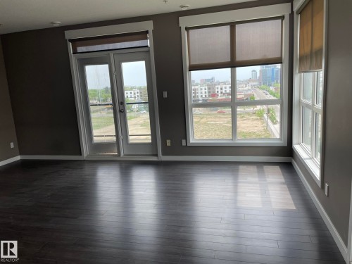 Spacious interior featuring dark wood-finish flooring, neutral gray walls, and white baseboards - 504 10518 113 Street, Edmonton, AB - Indoor Photo Showing Other Room