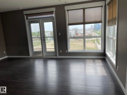 Spacious interior featuring dark wood-finish flooring, neutral gray walls, and white baseboards - 