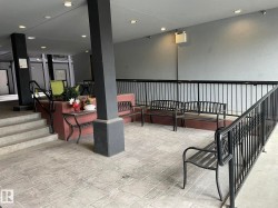 Covered outdoor patio area featuring stamped concrete flooring, black metal railings, and recessed ceiling lighting - 