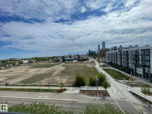 Urban landscape featuring a distant city skyline, multi-story residential buildings with balconies, paved roadways, and undeveloped land parcels - 504 10518 113 Street, Edmonton, AB - Outdoor With View