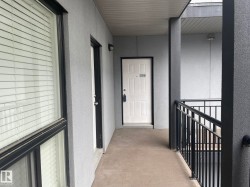 Entryway featuring a solid panel door with transom, textured exterior walls, and a black metal railing - 