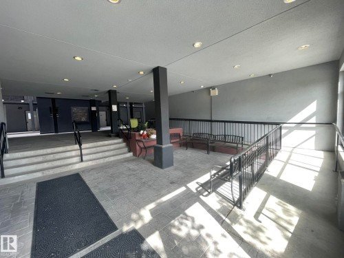 Covered outdoor common area featuring recessed lighting, a stone tile floor, and black metal railings - 504 10518 113 Street, Edmonton, AB - Indoor Photo Showing Other Room