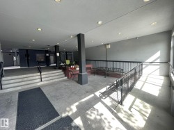Covered outdoor common area featuring recessed lighting, a stone tile floor, and black metal railings - 
