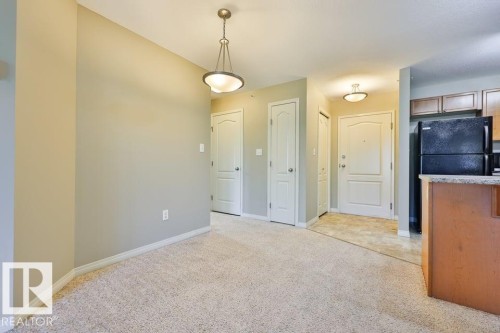 Carpeted living space featuring an overhead pendant light and a neutral color palette - #406 4903 47 Av, Stony Plain, AB - Indoor