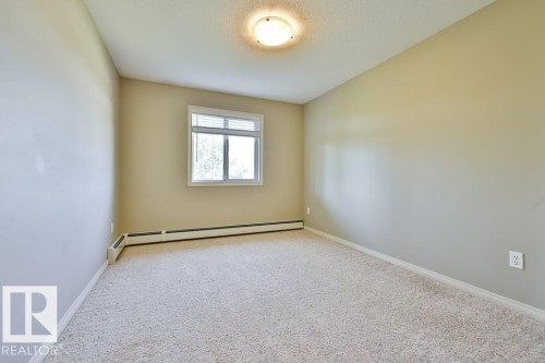 Carpeted room with a double-pane window featuring horizontal blinds - #406 4903 47 Av, Stony Plain, AB - Indoor Photo Showing Other Room