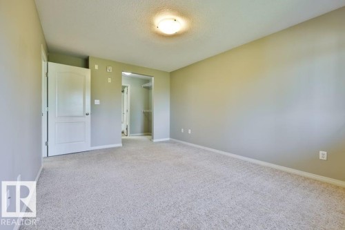 Light gray wall paint, textured ceiling, and light-colored carpeting - #406 4903 47 Av, Stony Plain, AB - Indoor Photo Showing Other Room
