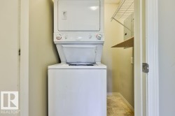 Dedicated laundry area featuring a white stackable washer and dryer unit, wire shelving, and an additional wall-mounted shelf - 