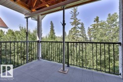 Balcony featuring a black wrought iron railing, textured gray flooring, and an exposed wood beam ceiling - 