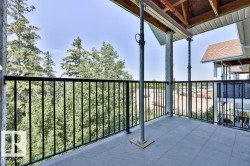 Balcony featuring a black metal railing, textured patio flooring, and exposed wood ceiling - 