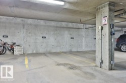 Underground parking space featuring concrete walls and ceiling, painted concrete flooring, and overhead fluorescent lighting - 