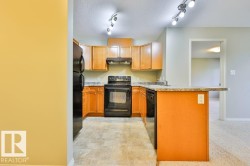 U-shaped kitchen with wood cabinetry and black appliances, complemented by a light-toned countertop - 