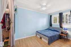Light blue room featuring wood-finish flooring, white baseboards, and white crown molding - 