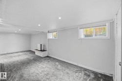 Spacious room featuring light gray walls, dark gray patterned carpeting, and recessed lighting - 