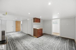 Spacious room featuring gray patterned carpet, recessed lighting, white walls, and dark wood-finish cabinetry - 