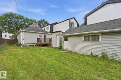 Expansive rear yard featuring green space, a detached garage with horizontal siding, and a separate shed - 