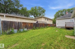 Expansive grassy yard area featuring a wooden privacy fence, a partial deck, and exterior siding - 