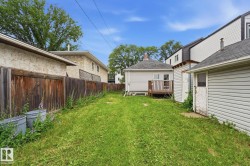 Expansive grassy yard with wood fencing, featuring a rear deck, and a detached garage with siding - 