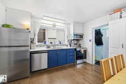 Kitchen featuring wood-finish flooring, white upper cabinetry, and contrasting blue lower cabinetry - 