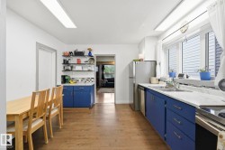 Kitchen featuring wood-finish flooring, white walls, and a full suite of stainless steel appliances - 