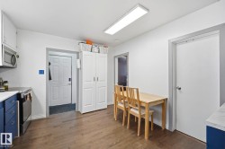 Kitchen featuring wood-finish flooring, white walls, and a built-in pantry cabinet - 
