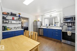 Kitchen featuring wood-finish flooring, white walls, and blue cabinetry - 