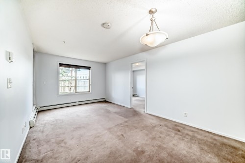 Carpeted room with a ceiling-mounted light fixture, window, and baseboard heating - 103 3315 James Mowatt Trail Sw, Edmonton, AB - Indoor Photo Showing Other Room
