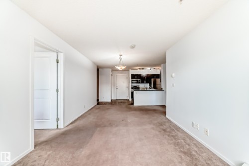 Open-concept living area featuring light brown carpeting and white painted walls - 103 3315 James Mowatt Trail Sw, Edmonton, AB - Indoor Photo Showing Other Room