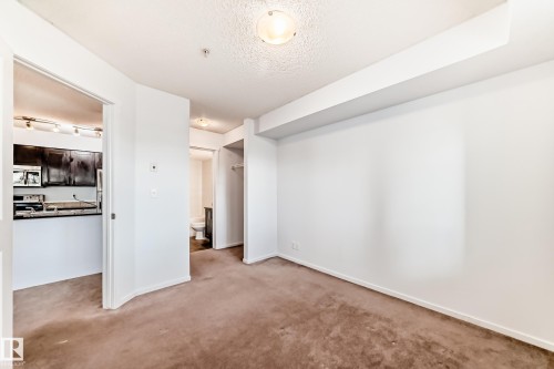 Carpeted living area with white walls and a ceiling-mounted light fixture - 103 3315 James Mowatt Trail Sw, Edmonton, AB - Indoor