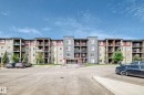 Multi-story residential building featuring balconies, stone façade accents, and ample exterior parking - 103 3315 James Mowatt Trail Sw, Edmonton, AB  - Outdoor With Balcony With Facade 
