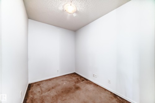 Compact interior room featuring white walls, brown carpeting, and a ceiling-mounted light fixture - 103 3315 James Mowatt Trail Sw, Edmonton, AB - Indoor Photo Showing Other Room